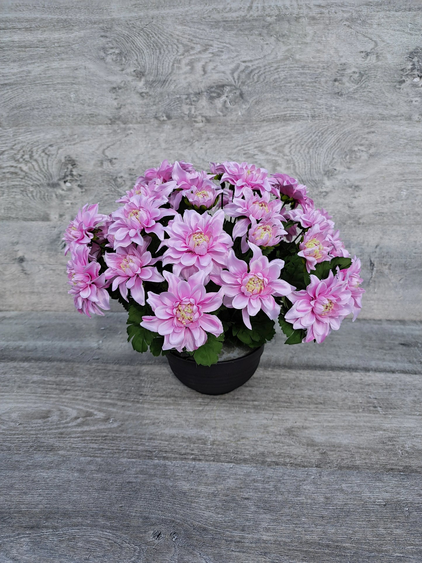 Artificial pink chrysanths flower arrangement for grave decoration.