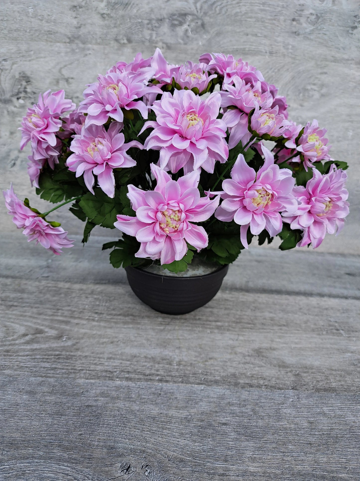 Artificial pink chrysanths flower arrangement for grave decoration.